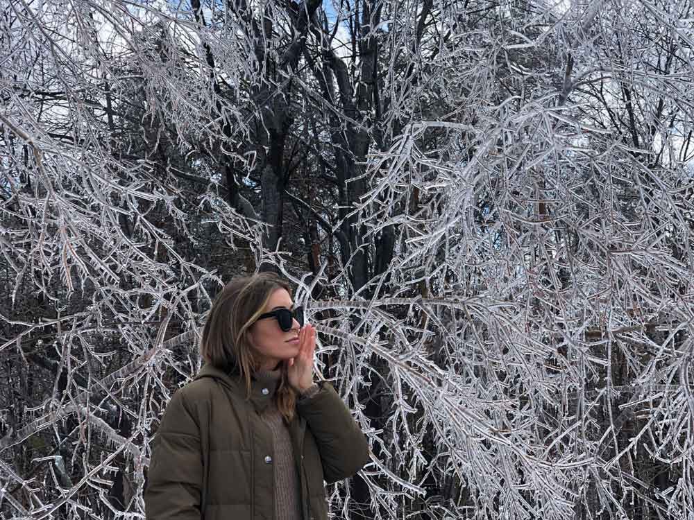 chica con gafas de Sol y abrigada y detrás el paisaje nevado